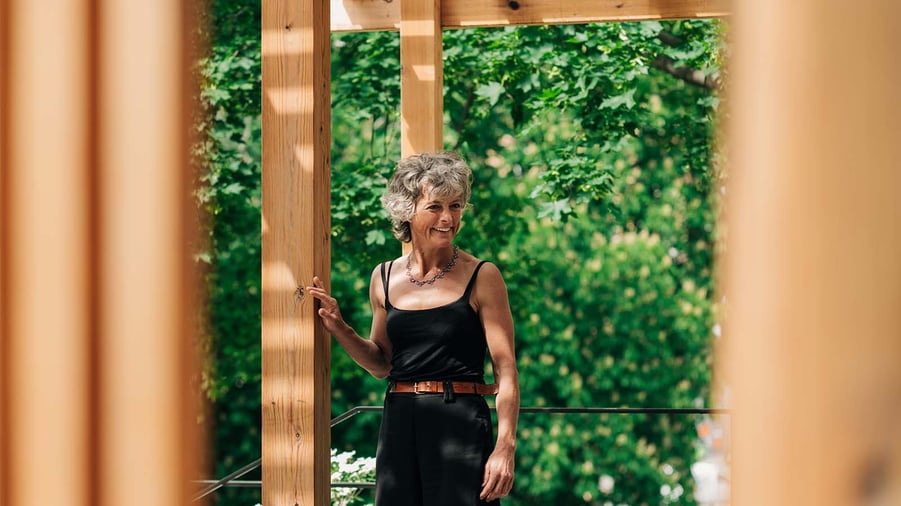 kvinna framför yogapaviljong i trä