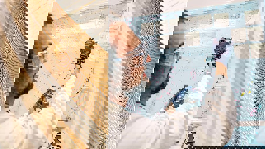 inzoomad bild på limträ och en man som arbetar i ett laboratorium