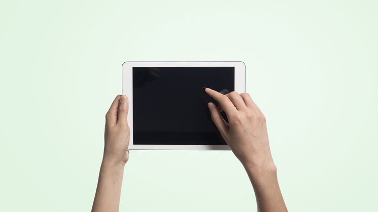 hand håller i läsplatta på grön bakgrund