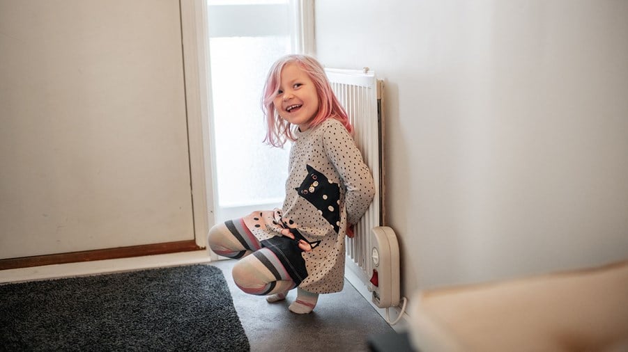 liten flicka värmer sig mot element